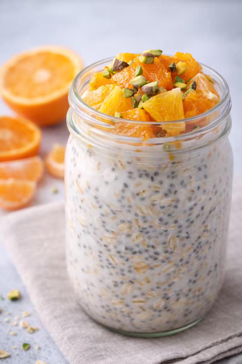 Haferflocken mit pflanzlicher Milch und frischen Zitrusfrüchten im Glas
