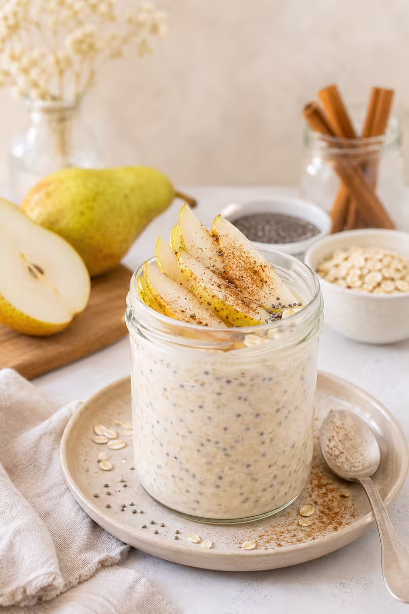 Cremige Overnight Oats im Glas mit Birnenscheiben Cremige Overnight Oats im Glas mit Birnenscheiben, Chiasamen und Zimt auf hellem Frühstückstisch