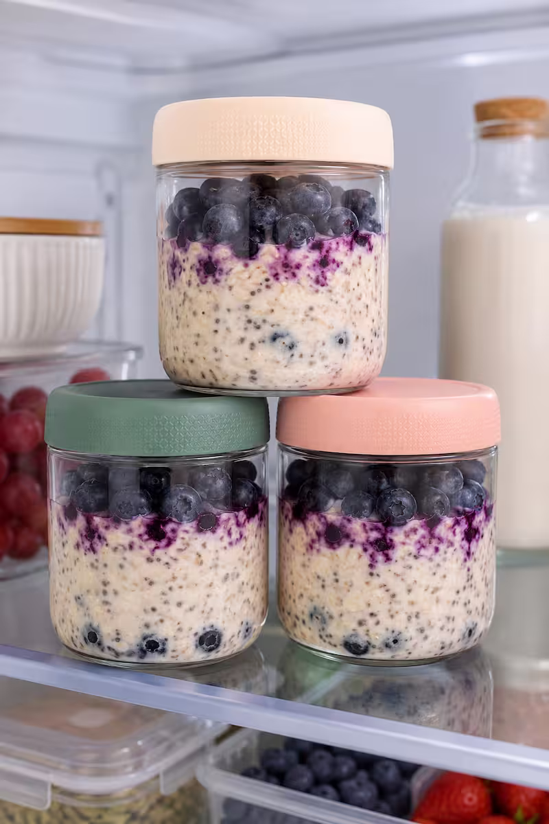 Drei Meal-Prep-Gläser mit Overnight Oats und Heidelbeeren im Kühlschrank