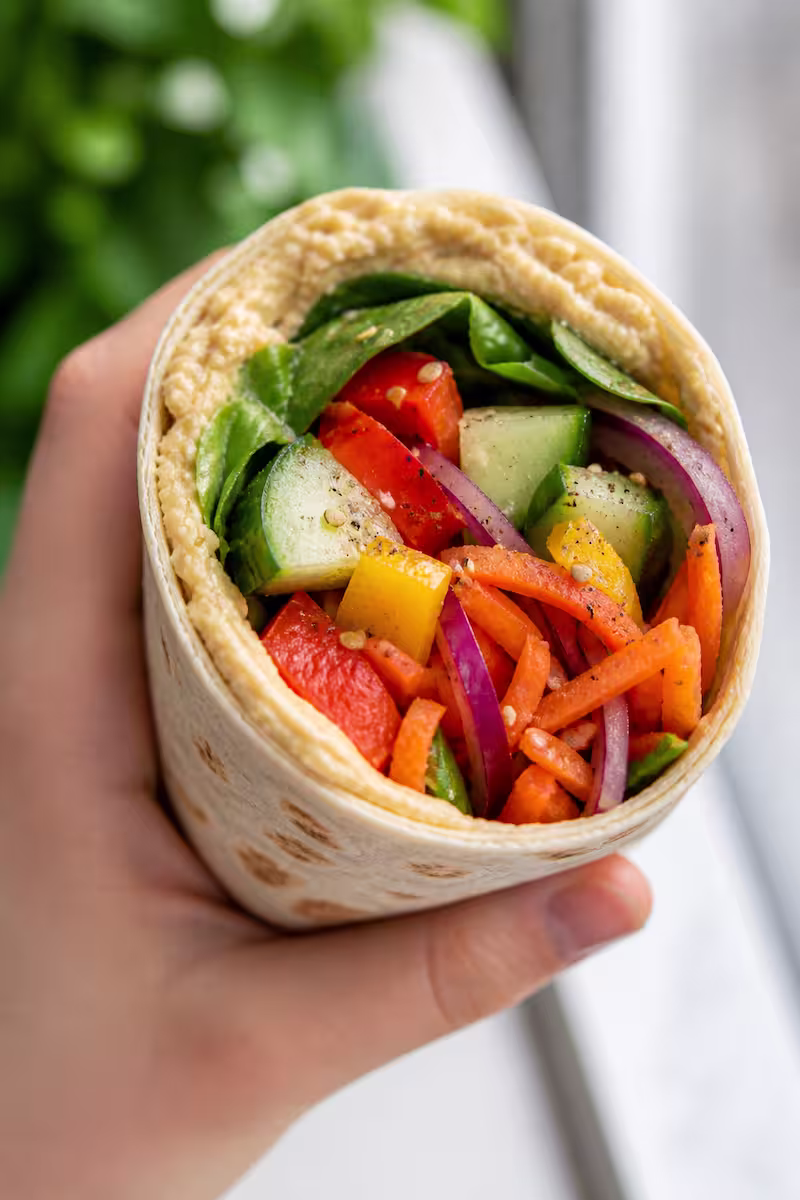  Hand hält Wrap, Fokus auf Füllung, natürliches Licht