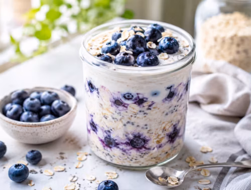 Cremige Overnight Oats Heidelbeeren mit Joghurt im Glas, garniert mit frischen Heidelbeeren und Haferflocken auf hellem Frühstückstisch bei natürlichem Tageslicht.